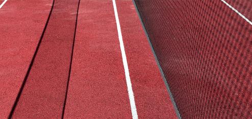 Nahaufnahme eines roten Tennisplatzes mit weißen Linien und einem Netz an der Seite.