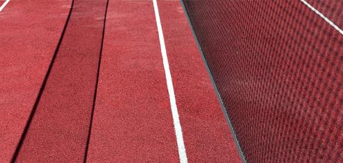 Nahaufnahme eines roten Tennisplatzes mit weißen Linien und einem Netz an der Seite.